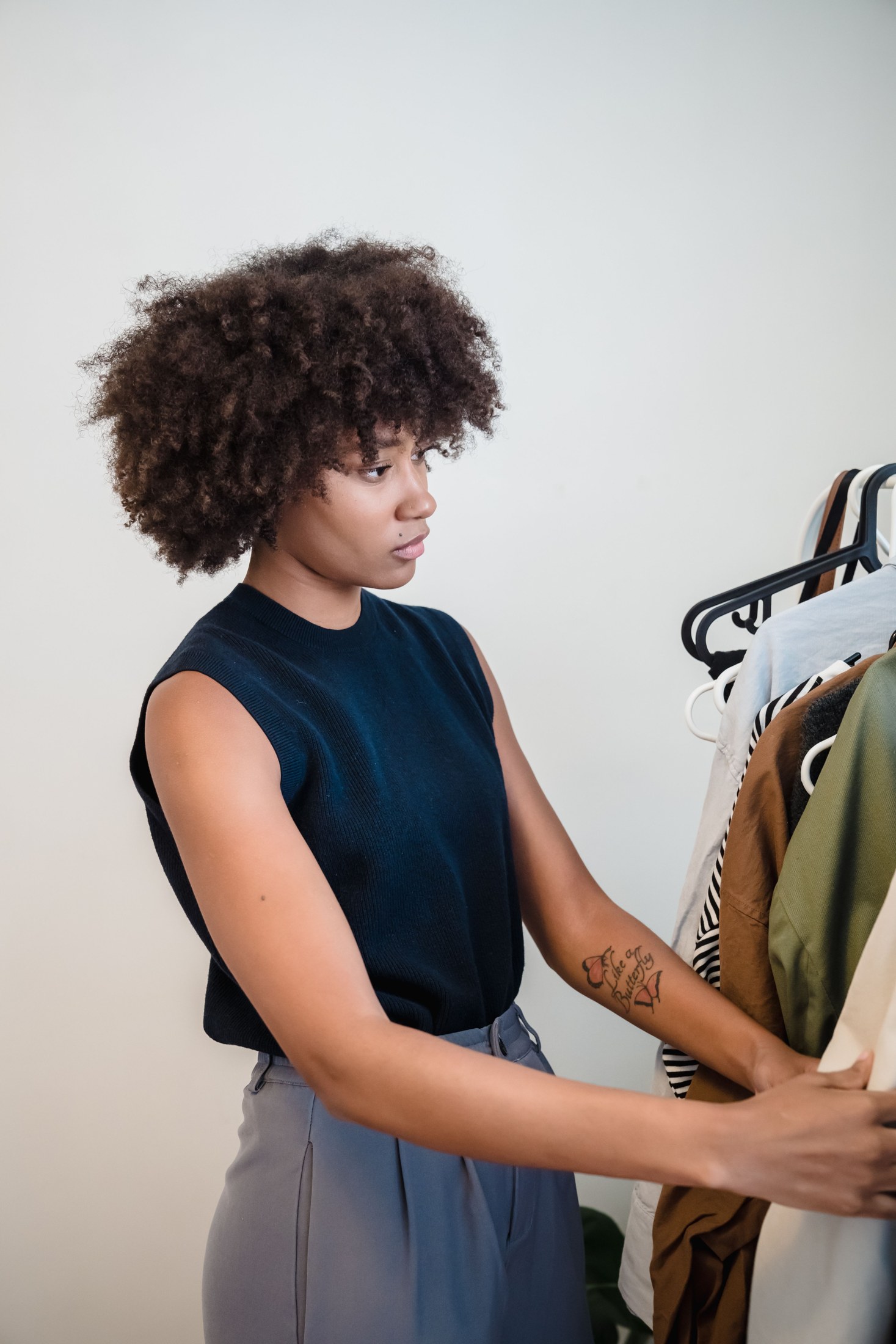 A person assessing clothing choices on a wardrobe rail