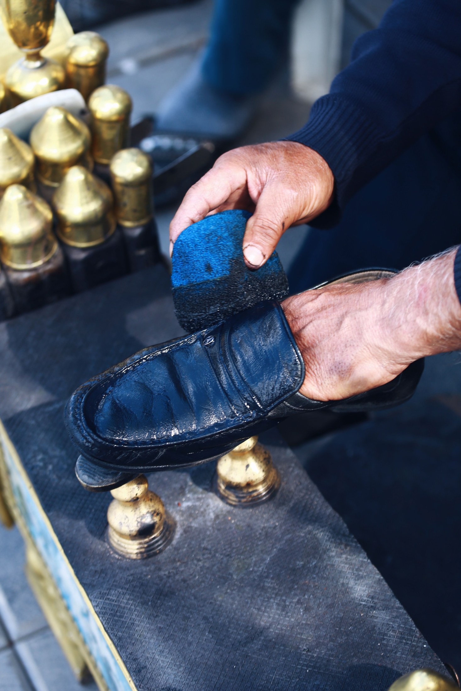 A person caring for a leather shoe with a brush
