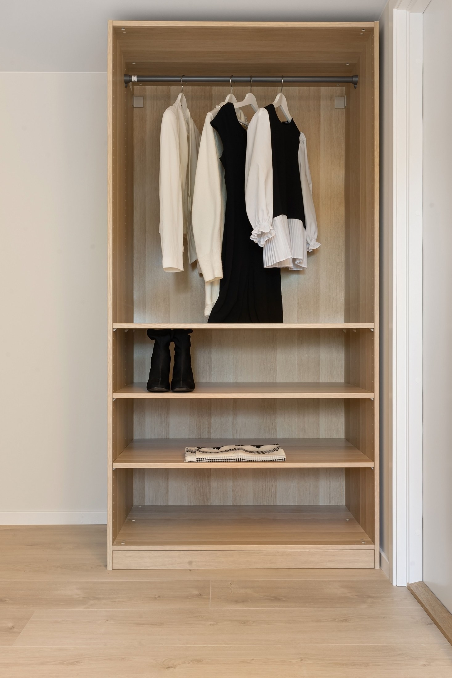 An open wooden wardrobe with accessible hanging clothes