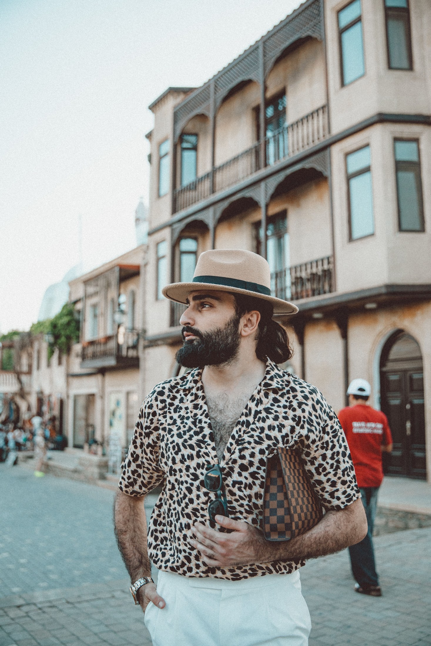 A man wearing a leopard-patterned shirt and hat on a Baku street
