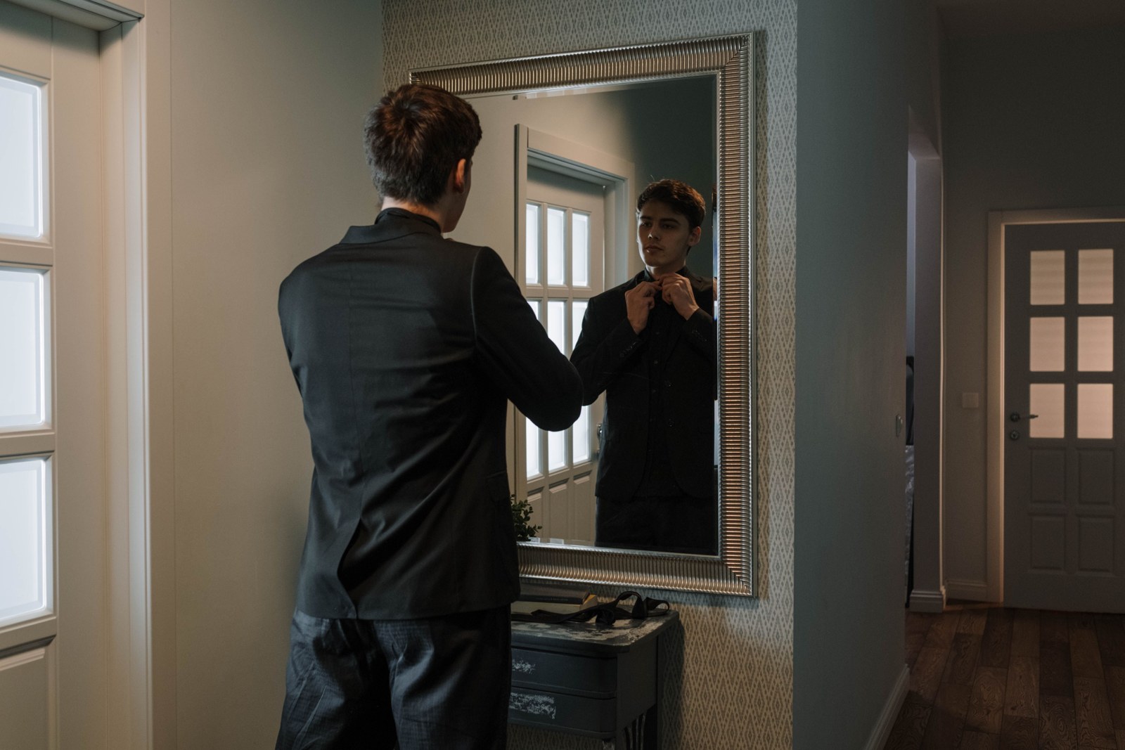 A man checking a dressed outfit in a home mirror