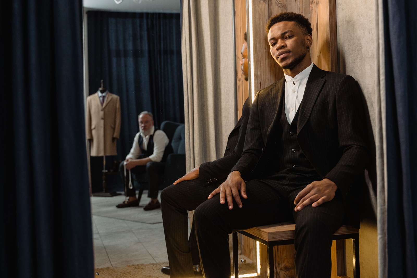 A client sitting in a tailor workshop with a mirror