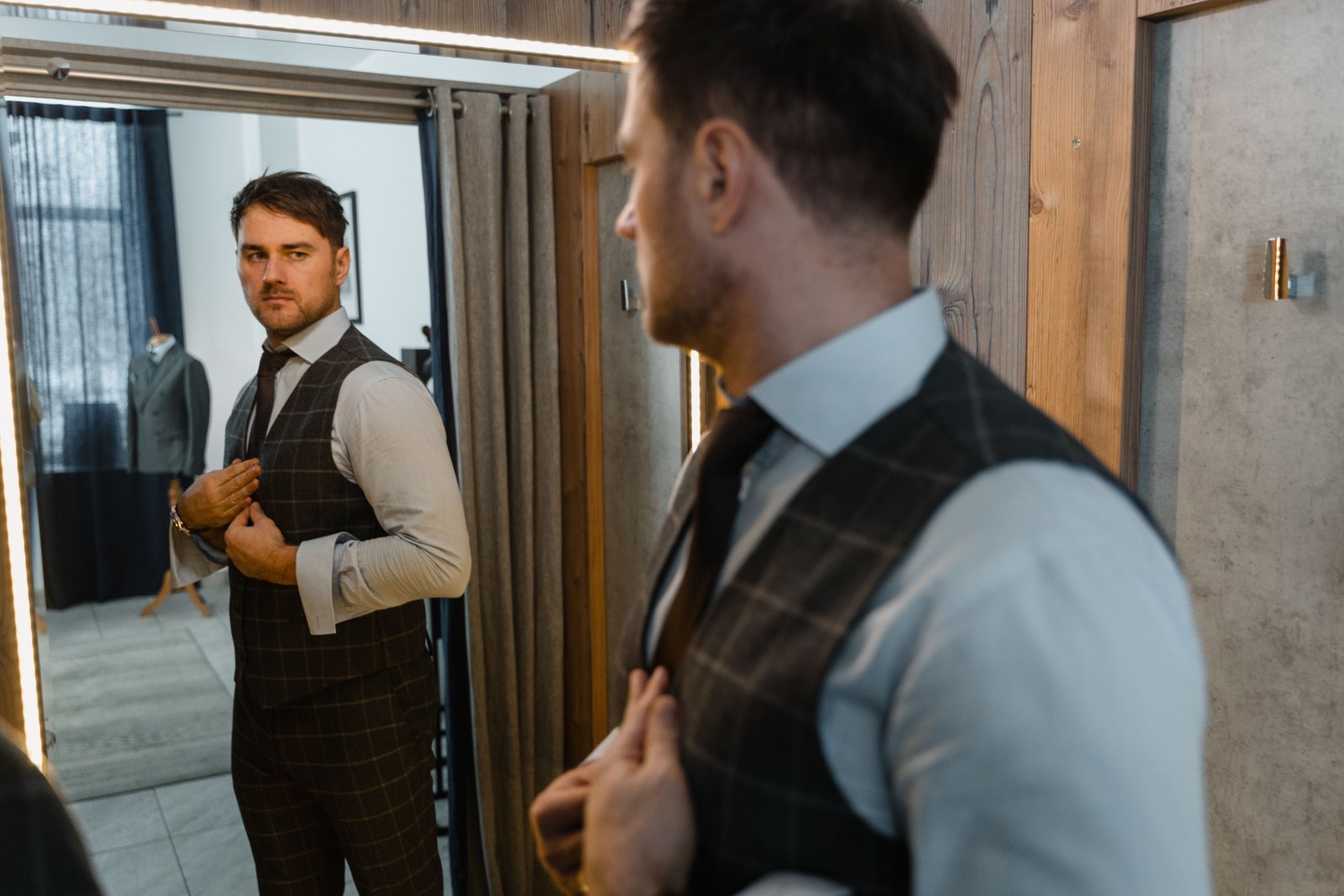 A man examining the fit of a suit in a mirror