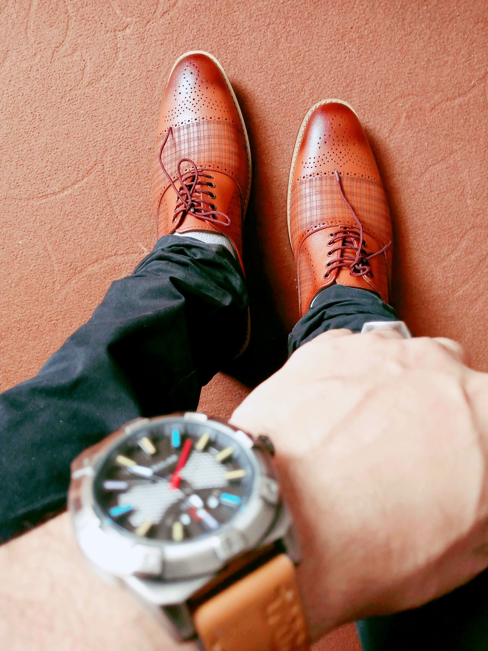 A worn outfit with brown leather shoes and a wristwatch