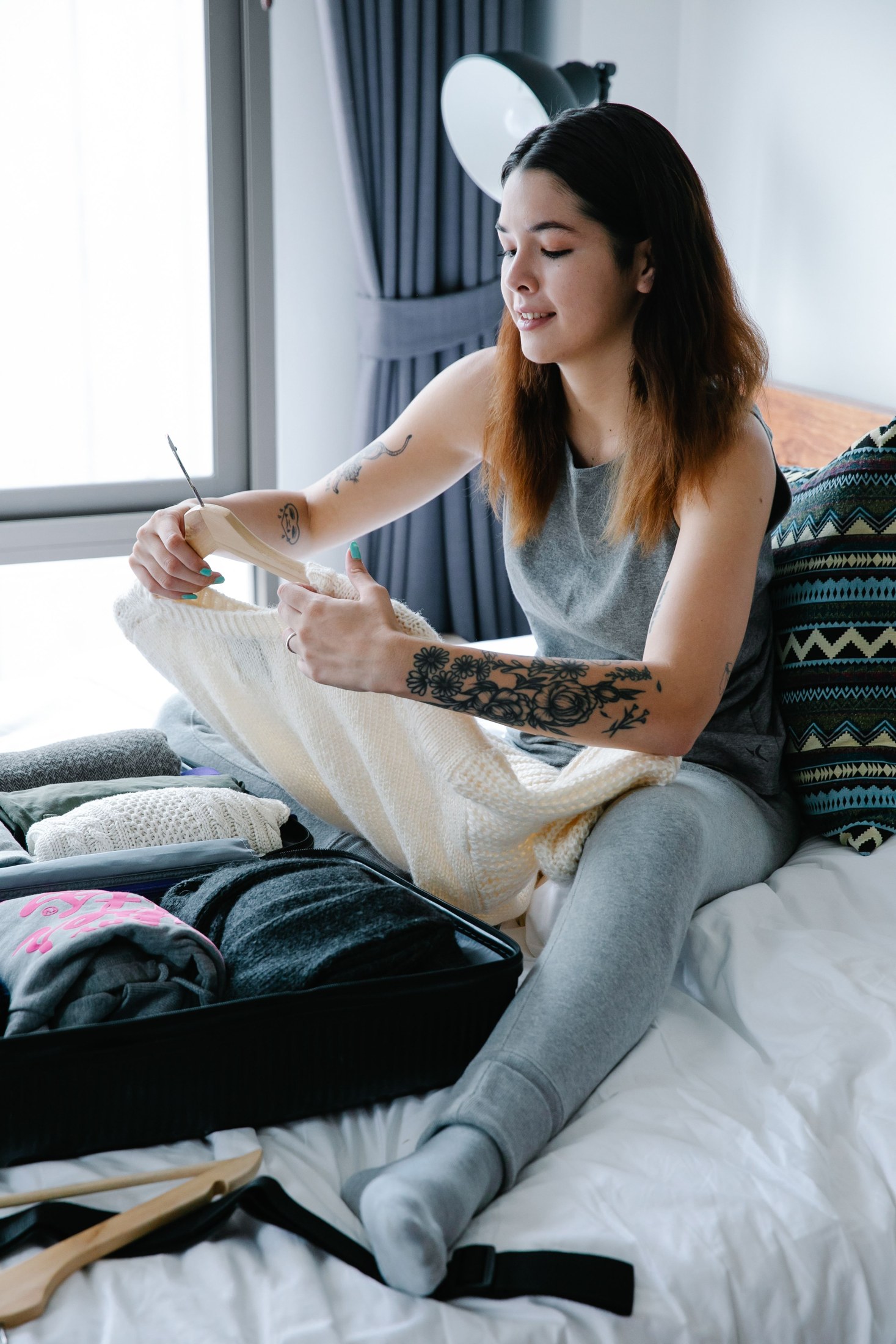 A traveler packing clothes beside an open suitcase