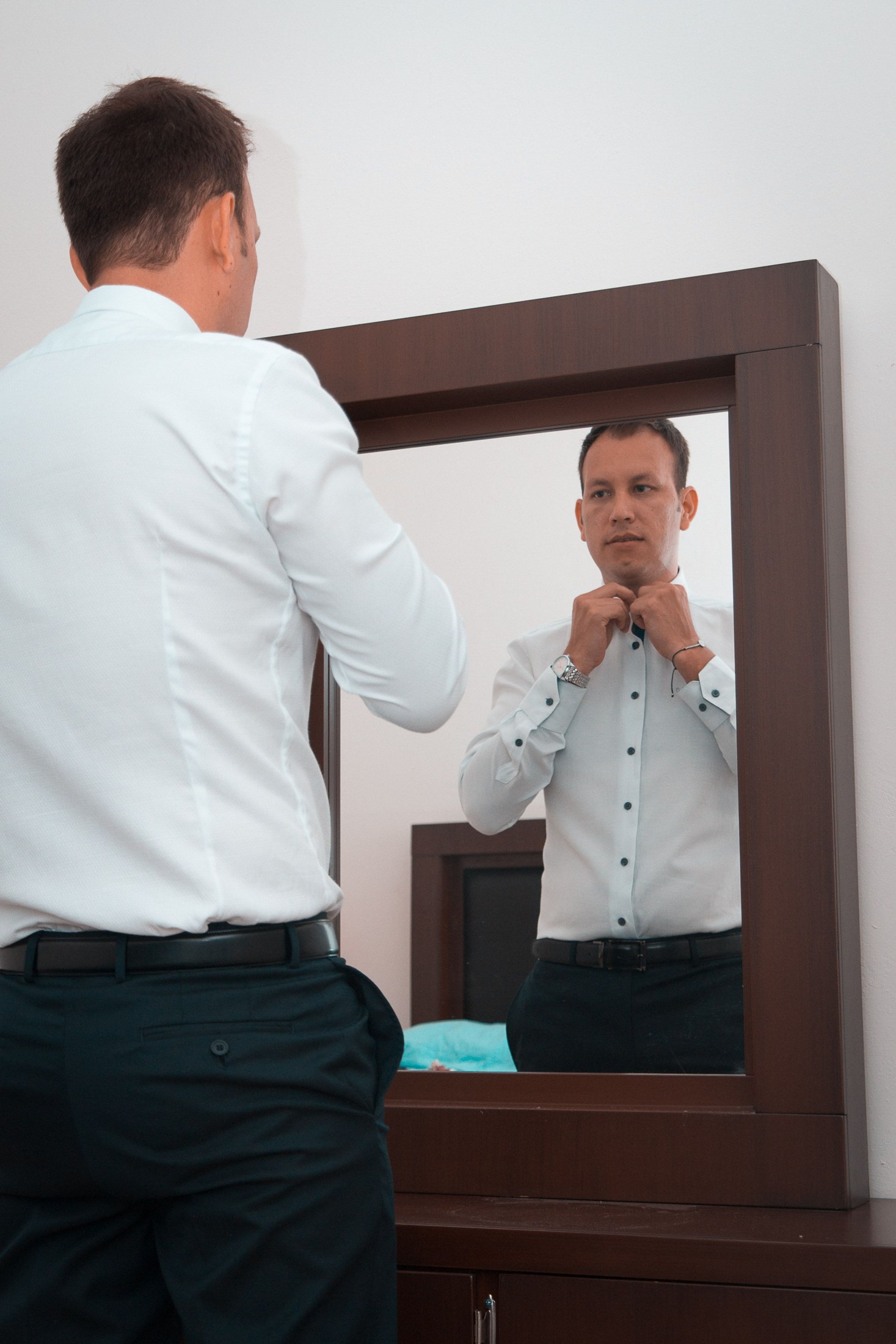 A man checking his shirt in a mirror