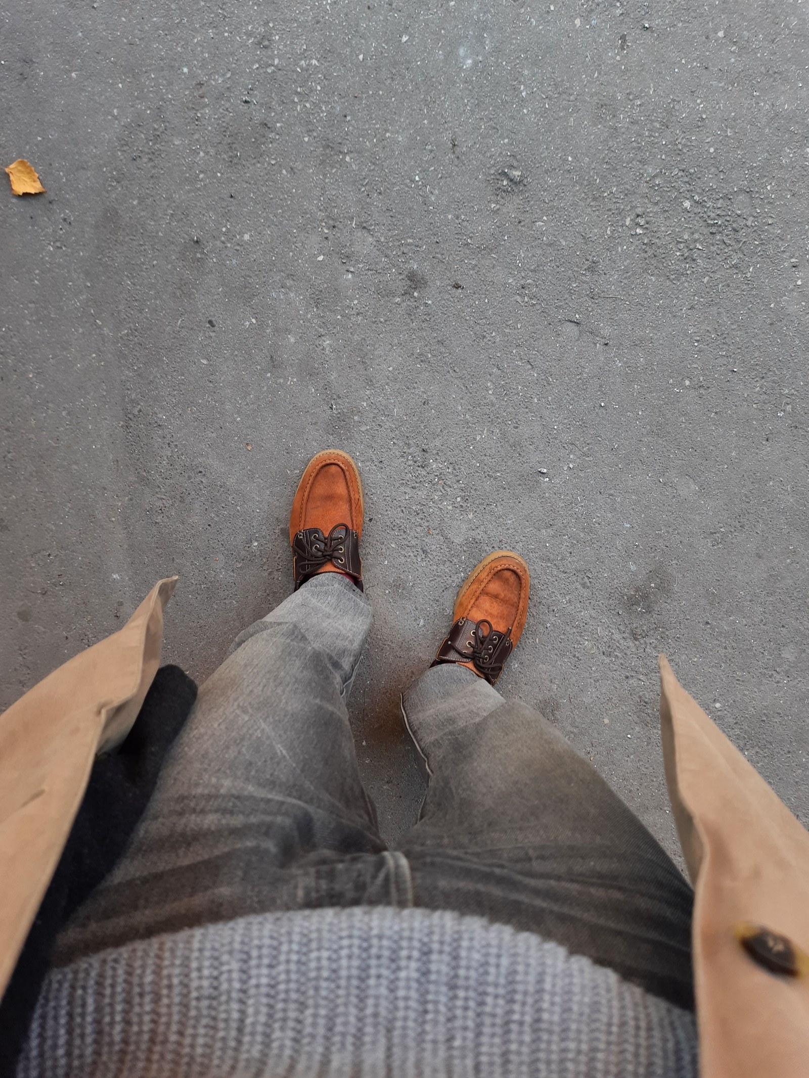 Brown leather shoes worn with jeans on a city surface