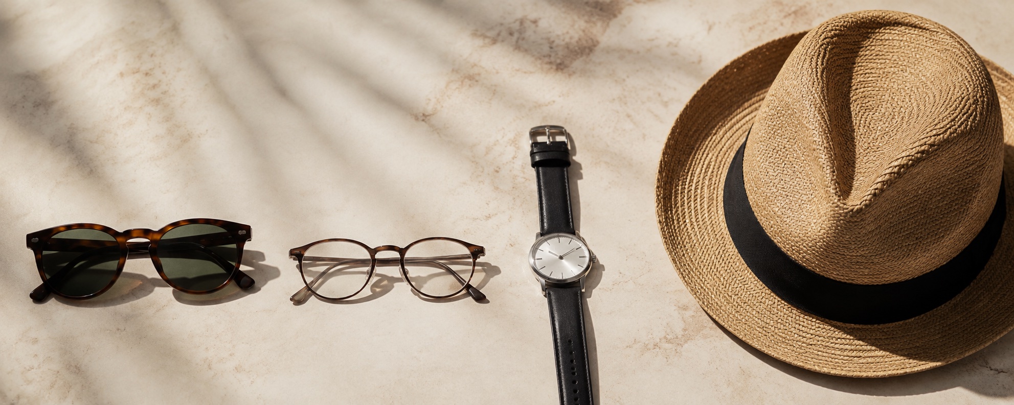 Glasses, a watch and a cap arranged on a light surface